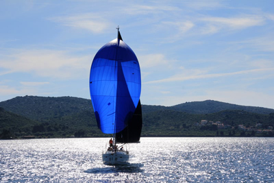 barco con una vela azul navegando en un embalse